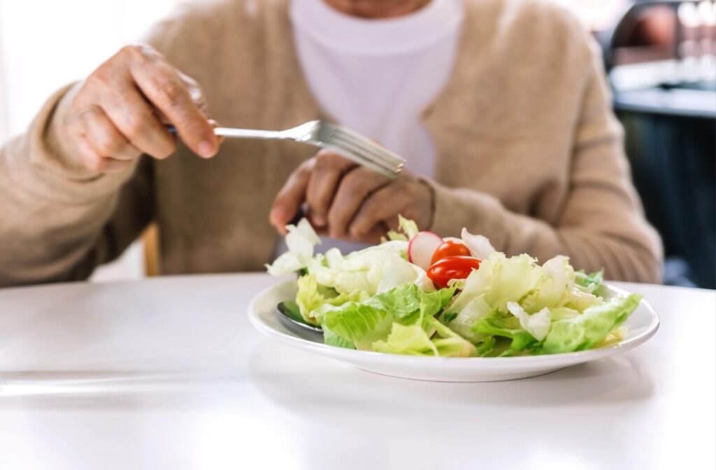 An older adult in senior living prepares to enjoy a colorful salad during mealtime