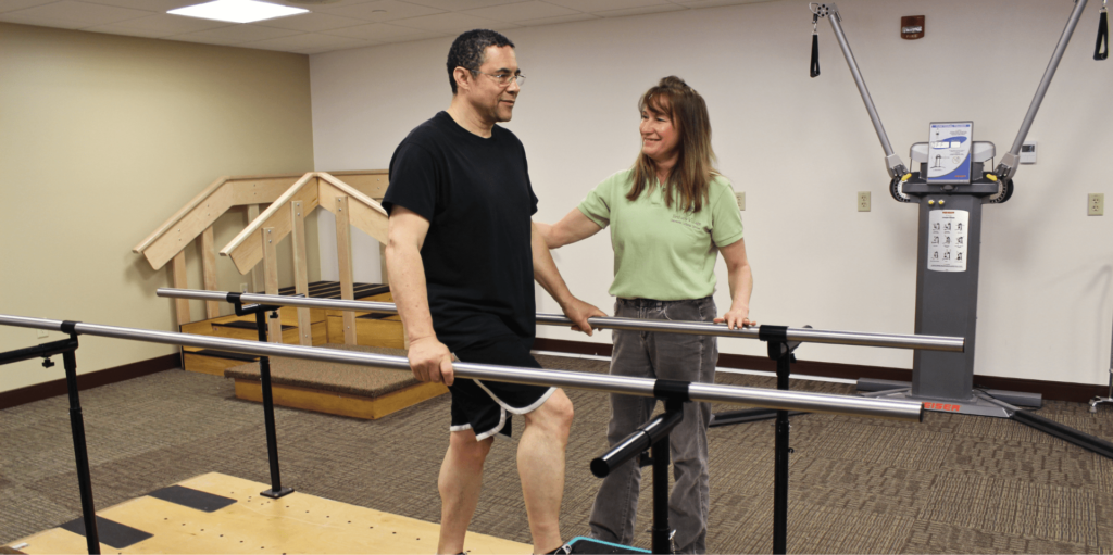 Bethany Rehab Center patient with aide walking with parallel bars