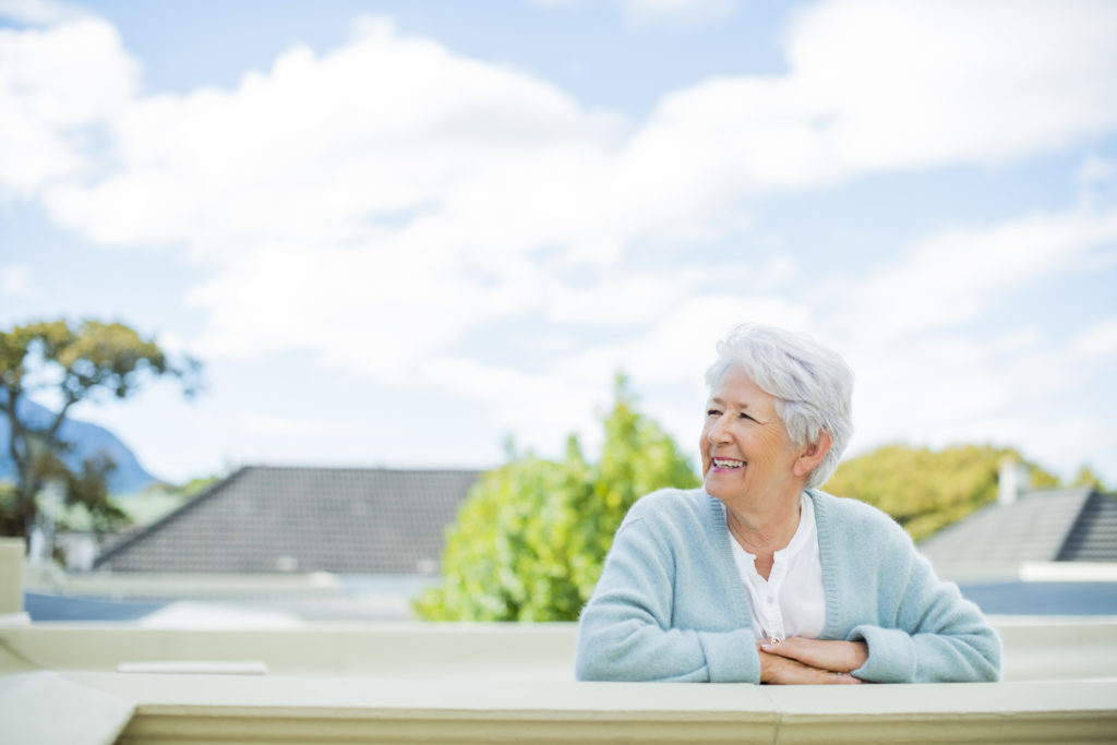 Happy senior woman looking away while leaning on terrace railing