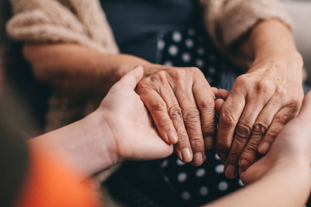 Close-up shot of grandmother's hands in younger woman's hands. 