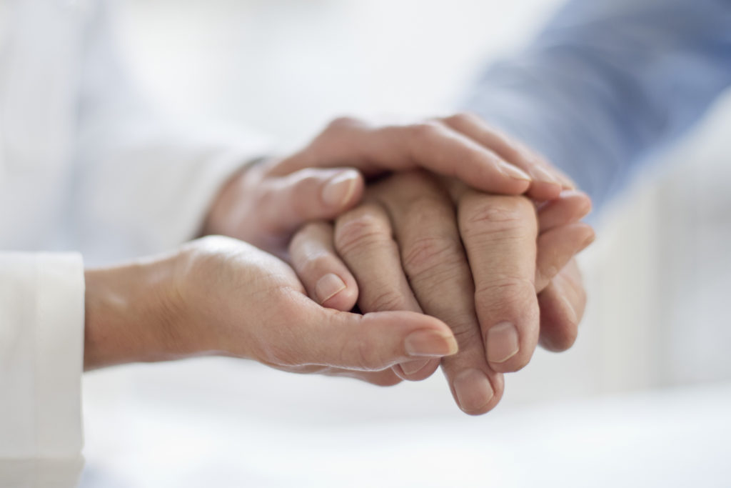 Female doctor holding patients hand.