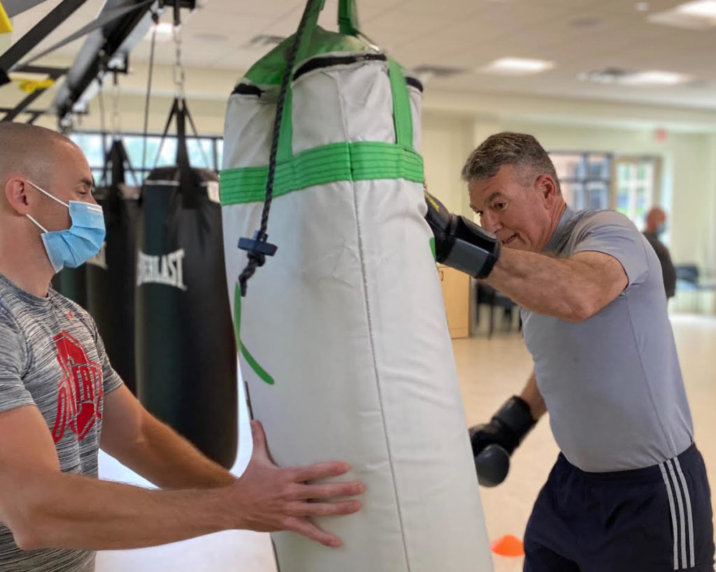 Alex Sheets, fitness instructor and participant in Rock Steady Boxing at Bethany Village punching boxing bag. 