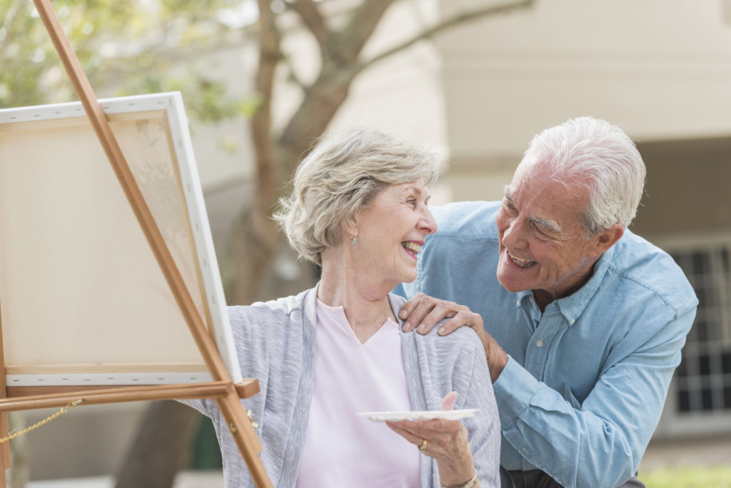 Senior woman painting picture, talking with husband