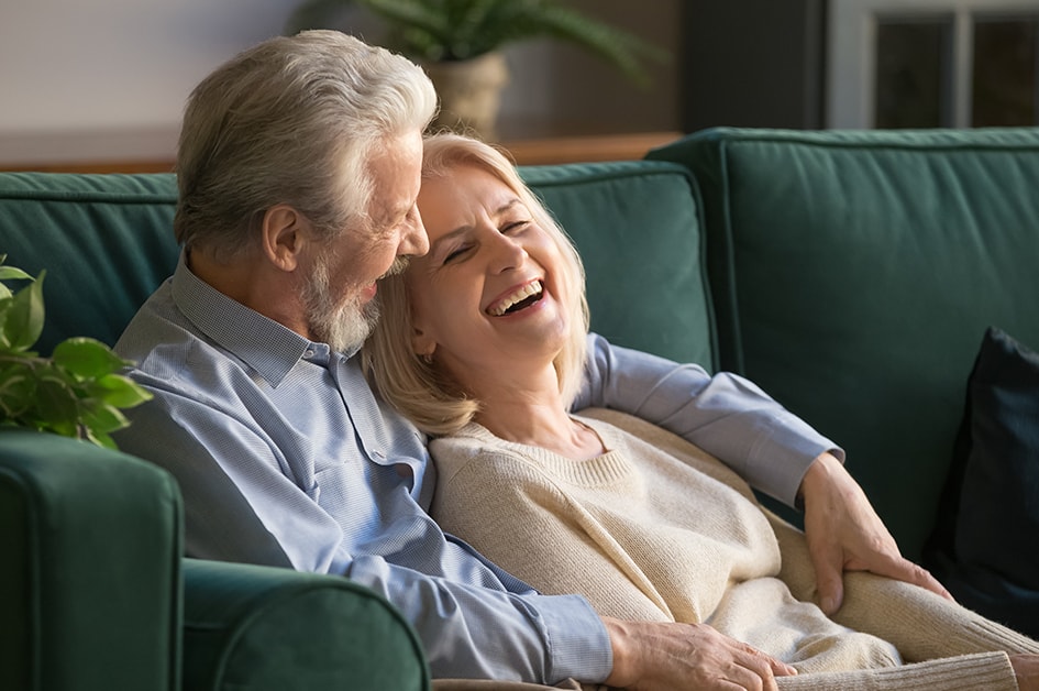 mature couple smiling sitting on couch