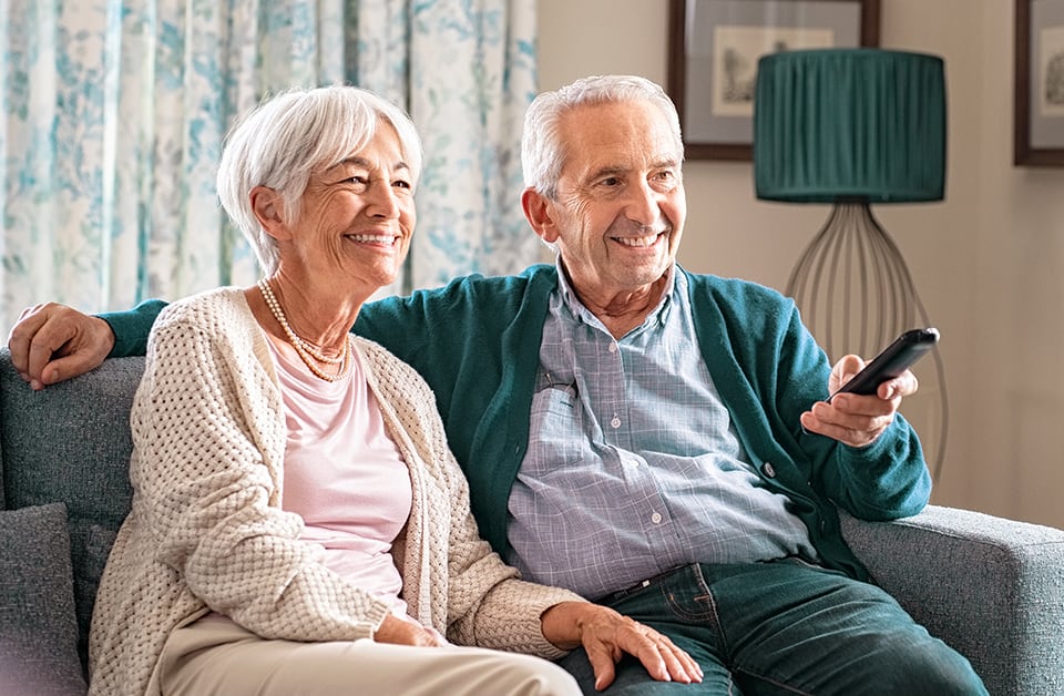 Mature couple sitting on couch watching tv