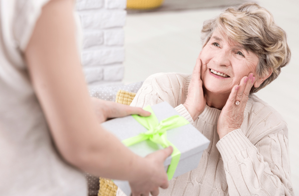 A female senior is surprised, receiving a gift from another woman