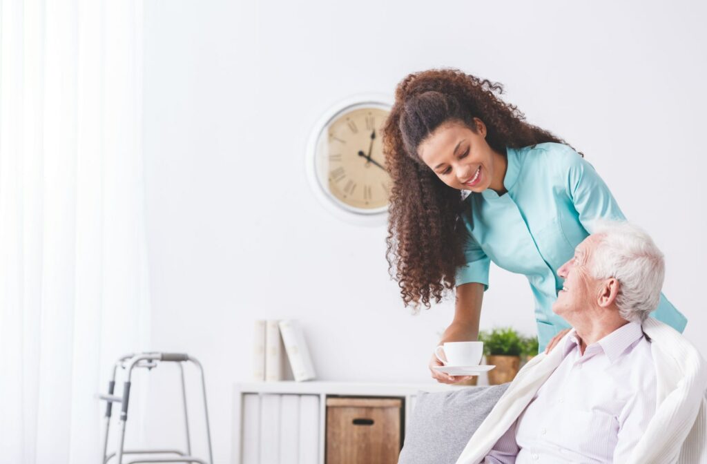 A female home healthcare employee assisting a male patient with his coffee