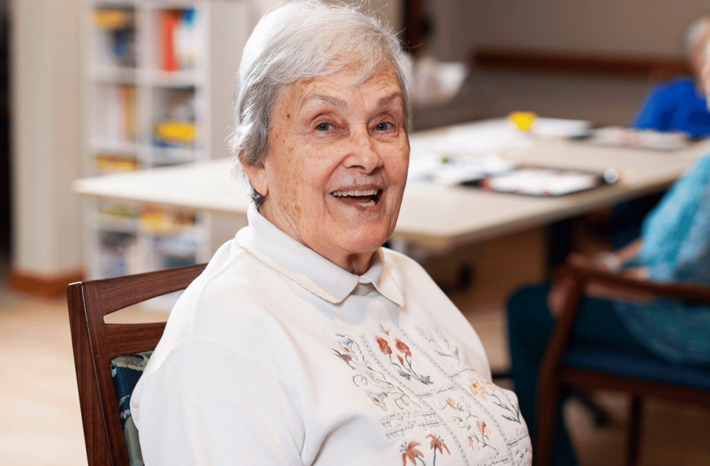 A senior living resident sitting in the commons area of a retirement community