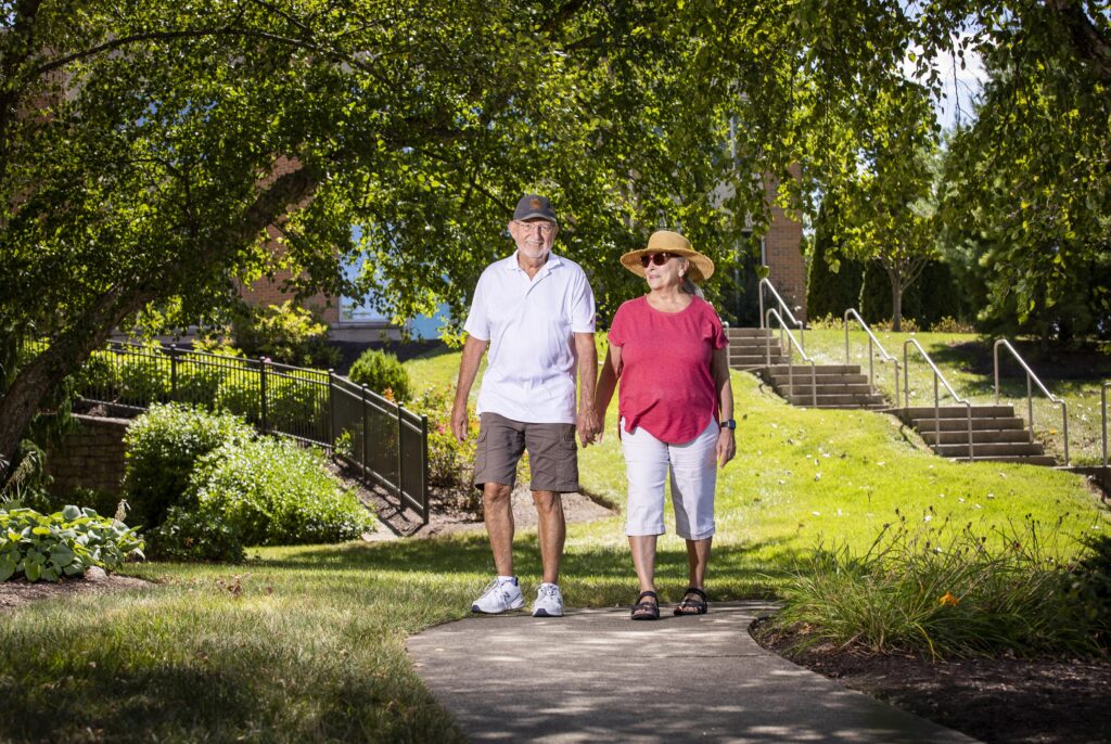 A senior couple walking through a peaceful outdoor area at a retirement community.