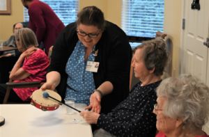 Bethany Village's music therapist helps a senior living resident play tambourine to improve range of motion in arms