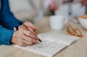 A senior woman working on a sudoku puzzle book