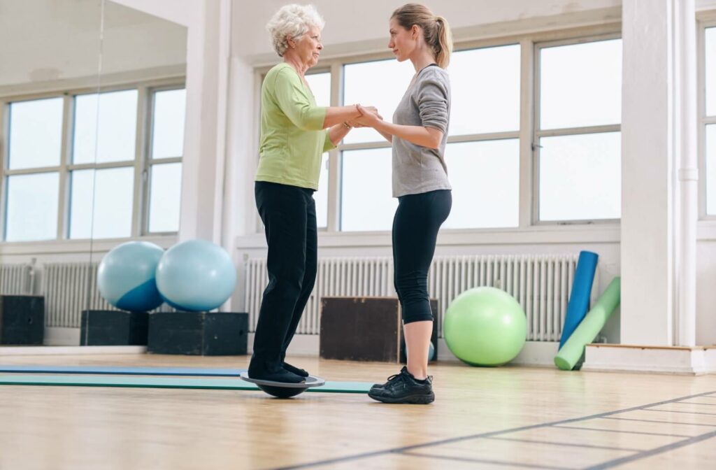 A senior woman practicing balancing with her trainer at an assisted living community.