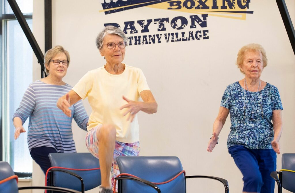 A group of seniors practicing balance exercises at a senior living community.