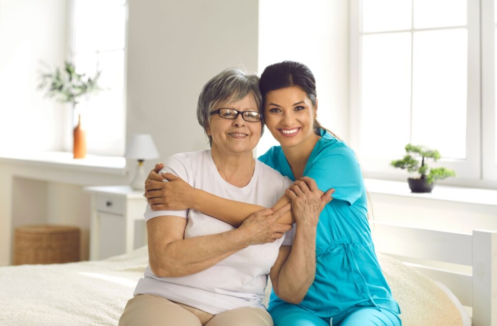 Supportive care taker embracing an older woman in a senior living community.