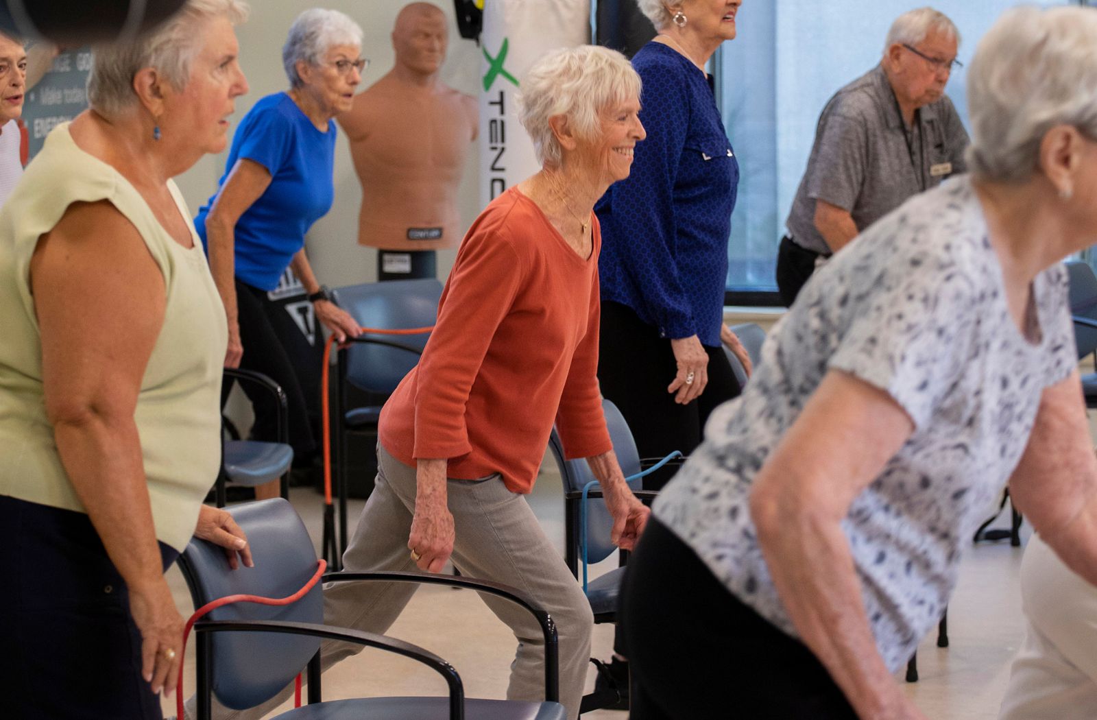 A group of older adults practicing balance exercises at a senior living community.