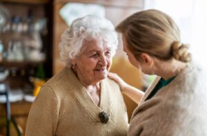 A senior woman smiling and enjoying a visit from her caregiving family member.