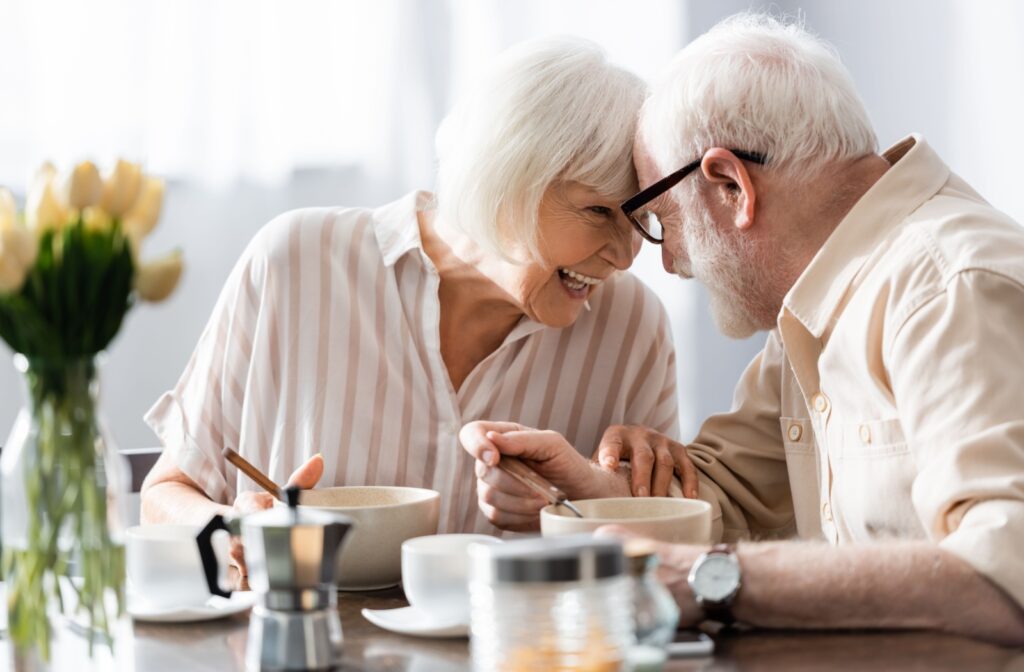 In the independent living community, a senior couple shares smiles and relishes their breakfast, creating a joyful and relaxed start to their day.