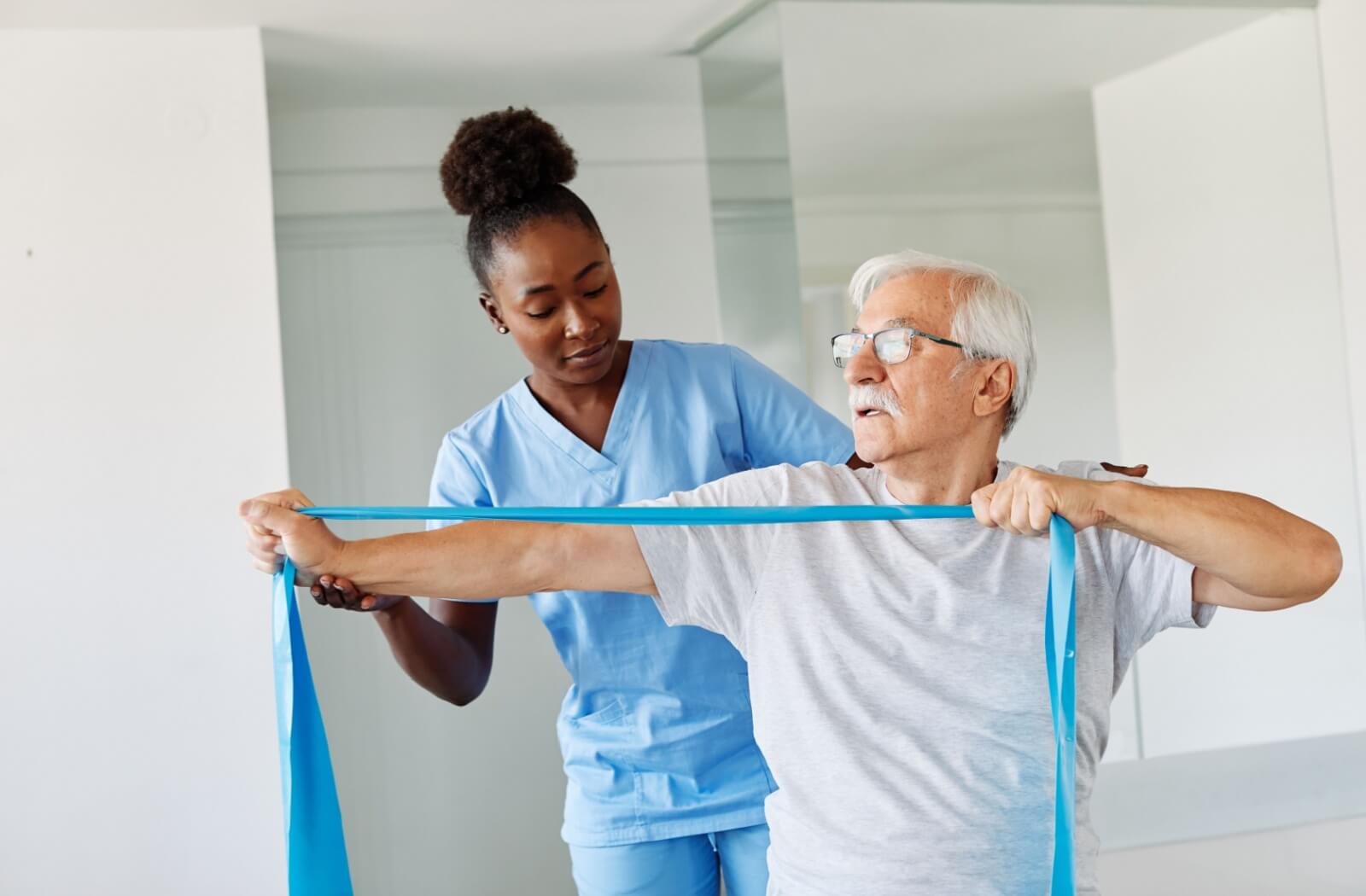 A physical therapist helps an older adult with stretches using a resistance band.