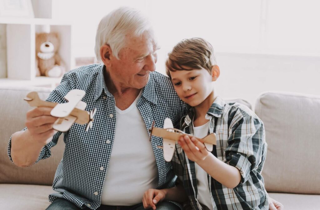a young boy and his senior grandfather play with toy planes