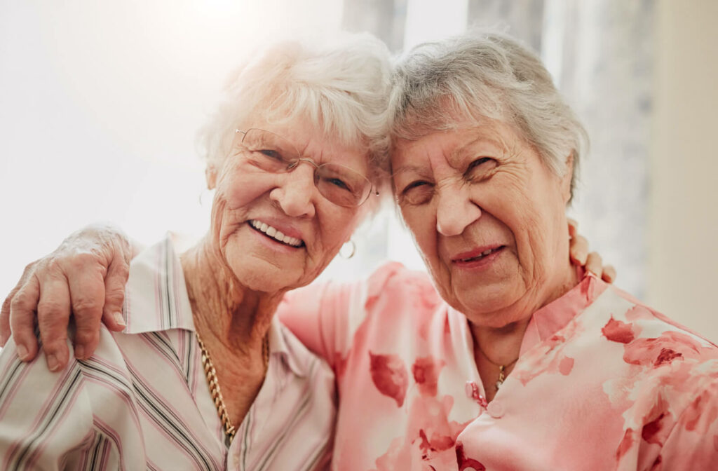 2 older adult friends touch foreheads and laugh while taking a photo