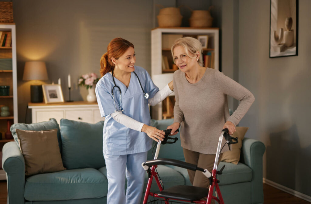 an at-home caregiver supports a senior woman with a walker in her home