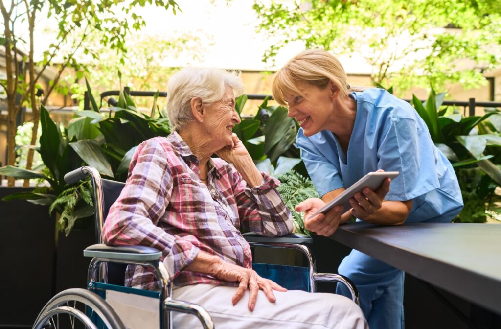 a senior in a wheelchair laughs with a carer