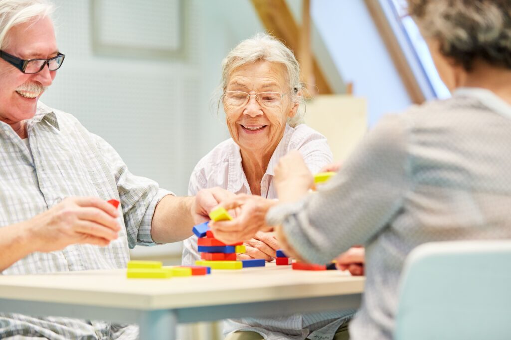 a group of seniors make a tower with blocks in memory care