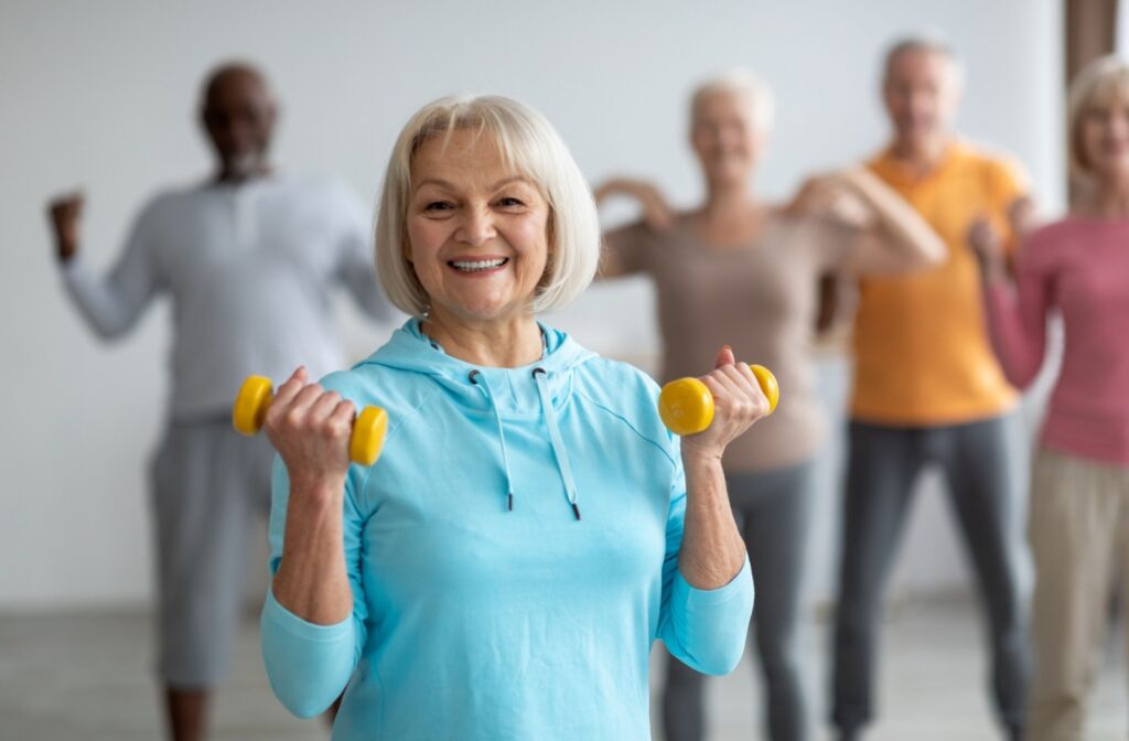 a senior holds two dumbells, smiling and exercising